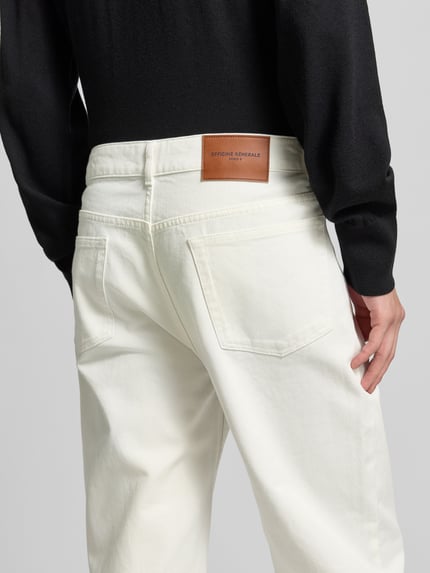 Mannelijk model draagt Regular Fit Jeans met knoopsluiting van Officine Générale, witte katoenen stof, 5-pocketdesign, detailopname achteraan.