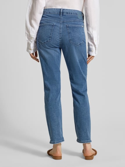 Frauenmodel trägt Cropped Jeans mit Eingrifftaschen Modell 'Dream' von MAC aus Baumwoll-Elasthan-Mix in mittlerem Blau, Ganzkörperansicht Rückansicht, Bundweite bei Größe 36/27: 41 cm, Innenbeinlänge: 70 cm.