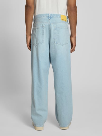 Männermodel trägt Baggy Jeans aus reiner Baumwolle Modell 'JAAMEO' von Armedangels in hellblauem Denim mit Label Patch, Ganzkörperansicht Rückansicht.