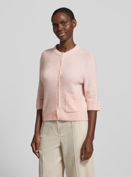 Frauenmodel trägt Cardigan mit Eingrifftasche Modell 'Dathena' von OPUS in zartem Rosa; Material-Mix mit Mohair-Anteil, Knopfleiste, gerader Schnitt, Rundhalsausschnitt, gerippte Abschlüsse; Ganzkörperansicht von vorne.
