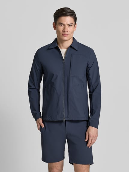 Männermodel trägt Regular Fit Jacke mit Umlegekragen Modell 'Motion' van SCANDINAVIAN EDITION, elastische materiaalmix, tweewegritssluiting, napoleonzak en steekzakken, lengte 73 cm, schouderbreedte 45 cm, borstwijdte 50 cm, mouwlengte 66 cm, donkerblauw, gladde textuur, ganzebodyvooraanzicht.