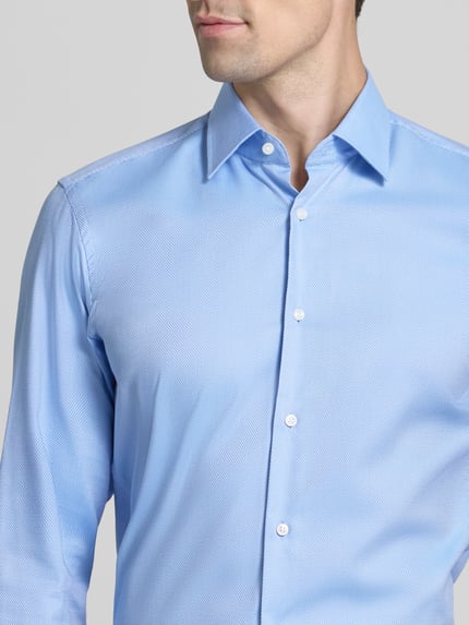 Männermodel trägt Regular Fit Businesshemd mit Kentkragen von BOSS, feine Webstruktur, unifarben, Knopfleiste, Nahaufnahme Oberkörper.