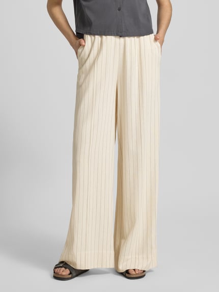 Vrouwenmodel draagt Loose Fit Pants met steekzakken model 'tascha' van Gestuz, viscosemix met linnen, uitlopend model, elastische band, maat 36, binnenbeenlengte 81 cm, lichte kleur, verticale strepen, zachte textuur, helemaal vooraanzicht.