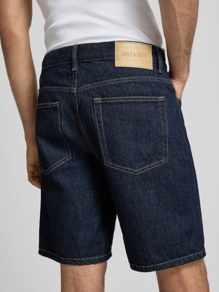 Mannelijk model draagt Regular Fit Jeansshorts uit puur katoen model 'EDGE' van Only & Sons in denimlook met labelpatch, 5-pocketmodel, riemlussen en knoopsluiting, materiaalverwerking twill, detailopname achteraan