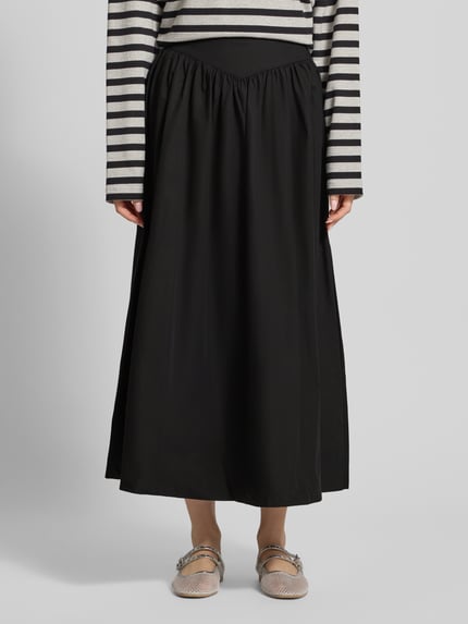 Frauenmodel trägt schwarzen Midirock mit A-Linie aus reiner Baumwolle, seitlicher Reißverschluss, Modell 'SALLY' von Topshop, Bundweite 35 cm, Ganzkörperansicht von vorne.