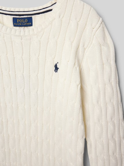 Produktfoto, cremefarbener Strickpullover mit Zopfmuster und Label-Stitching von Polo Ralph Lauren Kids aus reiner Baumwolle, Nahaufnahme Oberkörper.