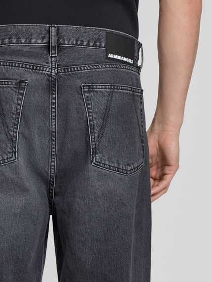 Mannmodel draagt Loose Fit Baggy Jeans uit puur katoen model 'JAAMEO' van Armedangels, denimlook, labelpatch, 5-pocketmodel, detailaufnahme achterkant.