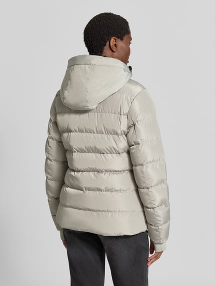 Vrouwenmodel draagt Regular fit gewatteerd jack in Model 'Synria' van Cars Jeans, Stiksels, capuchon met opstaande kraag, Steekzakken, ritssluiting, Ruglengte maat S: 65 cm, Schouderbreedte: 42 cm, Borstwijdte: 50 cm, Mouwlengte: 70 cm, Ganzijde achterkant.