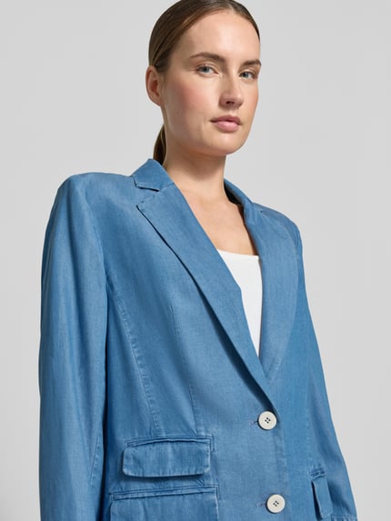 Frauenmodel trägt Relaxed Fit Blazer mit Pattentaschen von Marc Cain aus Lyocell in Denim-Optik mit Reverskragen und Knopfverschluss, Nahaufnahme Oberkörper. Rückenlänge 69 cm, Brustweite 41 cm, Ärmellänge 61 cm in Größe 36.