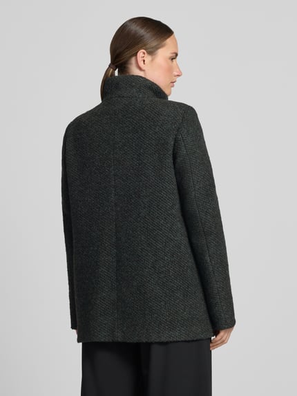 Frauenmodel trägt Jacke mit Stehkragen Modell 'JANINE' von Milo Coats, dunkler Material-Mix mit Struktur, Ganzkörperansicht Rückansicht.