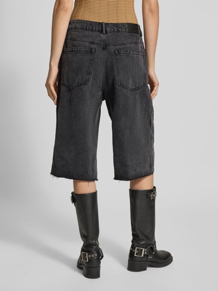 Frauenmodel trägt Jeansshorts im Destroyed-Look von Karo Kauer, schwarze Farbe, entspannter Schnitt, Eingrifftaschen, Ganzkörperansicht Rückansicht.