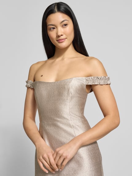 Kobiece modelka nosi szampańsko połyskującą sukienkę wieczorową Schimmerndes Abendkleid Modell 'Mindy' od Forever New, prosty fason, długość midi, off-shoulder, tekstura z lekkim połyskiem, zbliżenie na górną część sukienki, ujęcie przód.