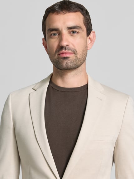 Männermodel trägt Slim Fit 2-Knopf-Sakko mit Paspeltaschen von MCNEAL, Viskose-Mix, cremefarben, Nahaufnahme Oberkörper.