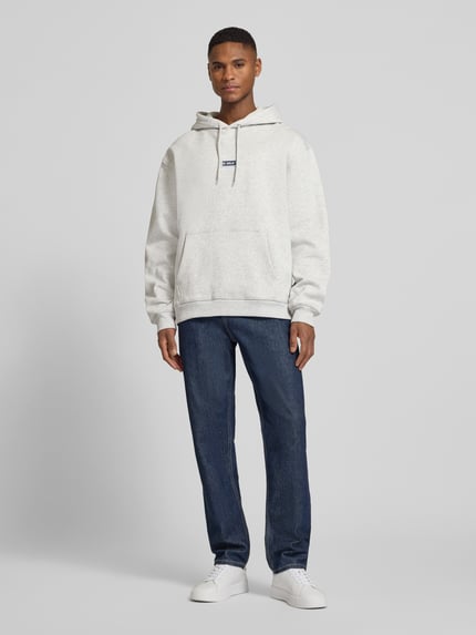 Männermodel trägt Hoodie mit Logo-Print Modell 'Chase' von Les Deux in Hellgrau, Loose-Fit aus Reine Baumwolle, Ganzkörperansicht von vorne.