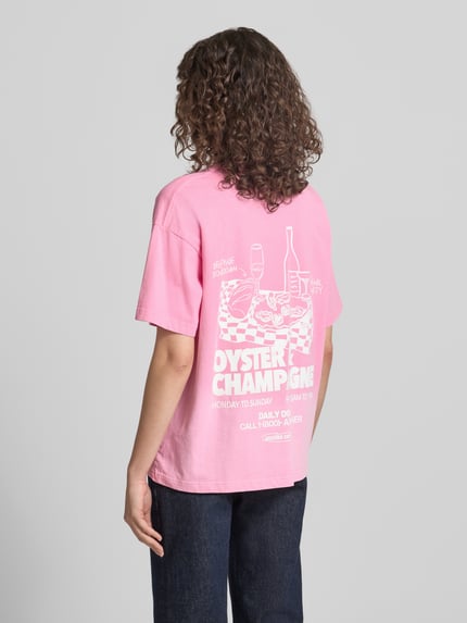 Frauenmodel trägt Oversized T-Shirt mit Logo-Print von ANOTHER COTTON LAB in Rosa, reine Baumwolle, lockerer Schnitt, Ganzkörperansicht Rückansicht