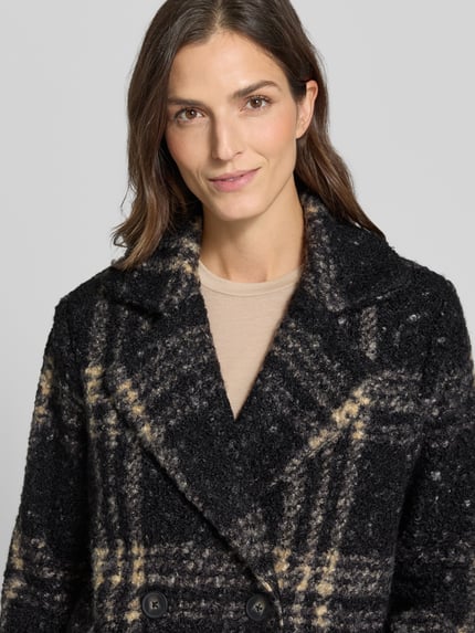 Frauenmodel trägt Mantel mit doppelreihiger Knopfleiste von SOYACONCEPT in mehrfarbiger Strickoptik mit kariertem Muster, Nahaufnahme Oberkörper.