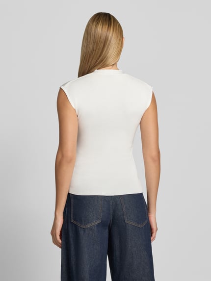 Frauenmodel trägt Stricktop mit V-Ausschnitt Modell 'CANELONS' von MANGO, weiß, feine Textur, taillierter Schnitt, Ganzkörperansicht Rückansicht. Viskose-Mix, Rückenlänge Größe S 56 cm.