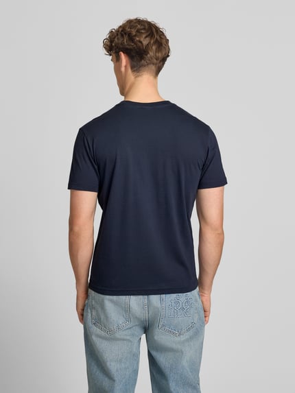 Männermodel trägt T-Shirt mit Label-Stitching mit Rundhalsausschnitt von CHAMPION in Dunkelblau, reine Baumwolle, Regular Fit, Rückansicht, Ganzkörperansicht.