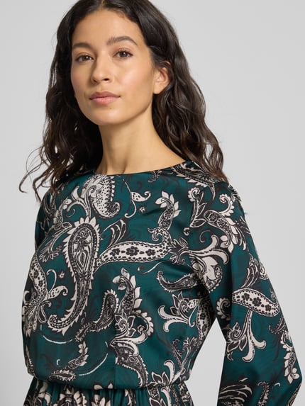 Frauenmodel trägt Cocktailkleid mit Rundhalsausschnitt von Rinascimento, Material-Mix mit Stretch-Anteil, körpernahe Passform, Plisseefalten, Nahaufnahme Oberkörper.