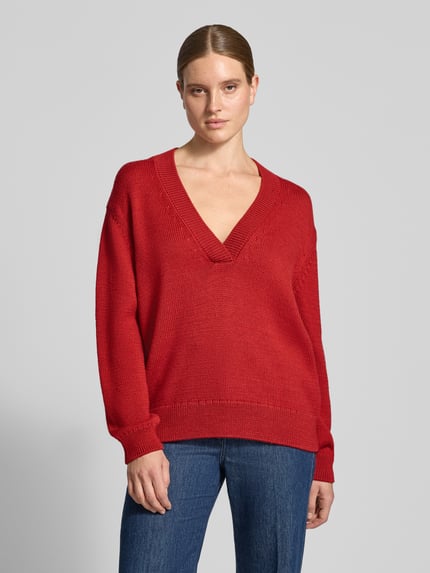 Frauenmodel trägt Oversized Pullover aus Lanawoll-Mix von Closed in Rot mit V-Ausschnitt, Strick-Optik, Ganzkörperansicht von vorne.