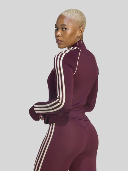 Frauenmodel trägt Slim Fit Trainingsjacke mit Logo-Detail von adidas Training in Dunkelrot mit beigen Streifen, Ganzkörperansicht Rückansicht.