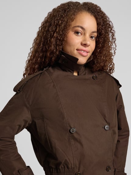 Vrouwenmodel draagt Regular Fit Jacke mit Kunstpelz van Gina Tricot in donkerbruin katoenmix, schoudertrensjes, reverskraag, dubbele knoopsluiting, verstelbare mouwsluitingen, elastische band, borstwijdte 58 cm, schouderbreedte 50 cm, mouwlengte 53 cm, ruglengte 50 cm, Nahaufnahme bovenlichaam.