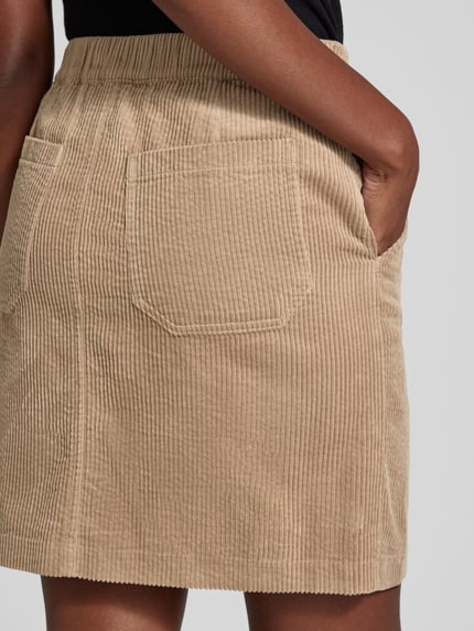 Frauenmodel trägt Mini-Rock Modell 'Reah horizon' von OPUS, beige, unifarben, matt, Cordstruktur, sichtbare Teilungsnähte, Rückansicht, Nahaufnahme Oberkörper.