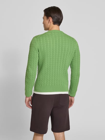 Männermodel trägt Regular Fit Strickpullover aus Baumwoll-Mix von Lacoste, Farbe grün, Zopfmuster, Unifarben, Ganzkörperansicht Rückansicht.
