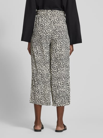 Frauenmodel trägt Culotte mit Bindegürtel Modell 'JOSA' von Vila im Loose-Fit mit elastischem Bund und seitlichen Eingrifftaschen, Bundweite bei Größe 36: 35 cm, Innenbeinlänge bei Größe 36: 91 cm, cremefarben mit schwarzen Punkten, Ganzkörperansicht Rückansicht.