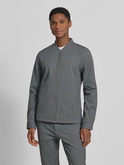 Męski model nosi Regular Fit Sweatjacke mit Stehkragen od Lindbergh w odcieniu szarości, gładka struktura, przód z zamkiem, widok całej sylwetki z przodu.
