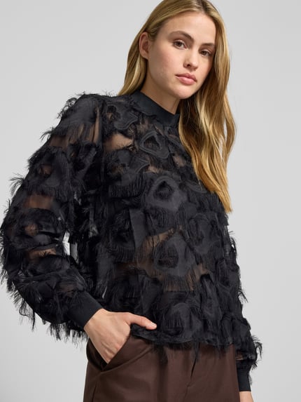 Vrouwenmodel draagt semitransparante blouse met franjes model 'DIO' van YAS, regular fit, opstaande kraag, detailopname bovenlichaam.