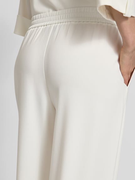 Frauenmodel trägt Regular Fit Weite HOSE mit Viskose-Anteil von s.Oliver BLACK LABEL, Optik: Unifarben, seitliche Eingrifftaschen, elastischer Bund, Material-Mix, Detailaufnahme Rückansicht.
