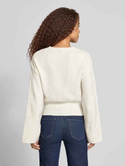 Frauenmodel trägt Pullover mit ausgestelltem Ärmelabschluss von ONLY, unifarben, Cropped-Länge, Strick, Ganzkörperansicht Rückansicht.