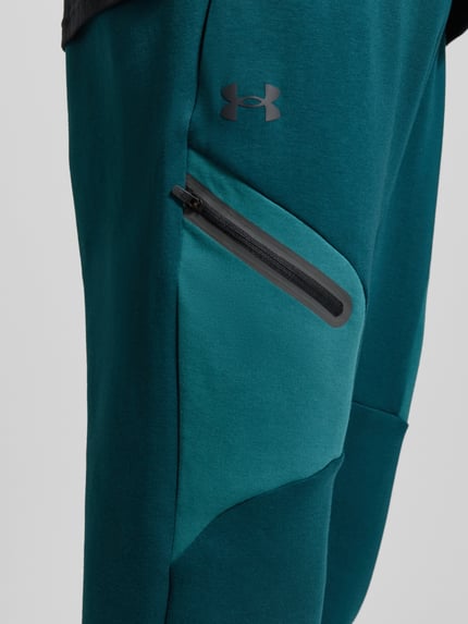 Produktfoto, Regular Fit Spodnie dresowe z logo-Print model 'Unstoppable' od Under Armour, elastyczna mieszanka materiałów z mieszanką bawełny, kieszeń na nogawce z zamkiem błyskawicznym, elastyczny pas i zakończenia nogawek, długość wewnętrzna nogawki w rozmiarze M: 73 cm, zielony odcień, gładka tekstura