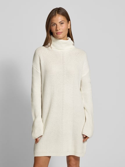Frauenmodel trägt Strickkleid mit Rollkragen von Liu Jo White in Creme, gerader Schnitt, grobe Textur, Knöpfe, Minikleid, Ganzkörperansicht von vorne.