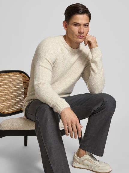 Männermodel trägt Strickpullover mit gerippten Abschlüssen Modell 'BLASIMON' von Jack & Jones Premium, Material-Mix mit Woll-Anteil, lockerer Schnitt, Rundhalsausschnitt, neutrale Farben, weiche Textur, Nahaufnahme Oberkörper.