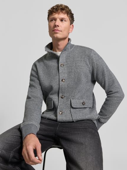 Männermodel trägt Strickjacke aus Wolle mit Stehkragen von RAGMAN in grauer Melange-Optik mit Strukturmuster, Nahaufnahme Oberkörper.
