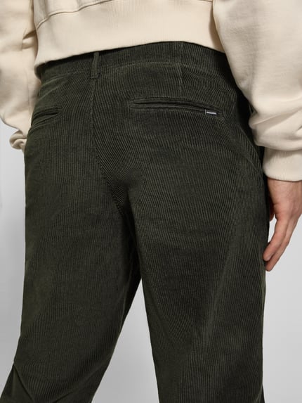 Männermodel trägt Regular Fit Cordhose mit Eingrifftaschen von JACK & JONES, Baumwoll-Elasthan-Mix, dunkles Grün, Nahaufnahme Rückansicht.
