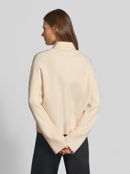 Vrouwenmodel draagt Loose fit pullover met schipperskraag model 'SABA' van VERO MODA in licht beige, zachte stof, dames pullover, volledige lichaamsopname achteraan.