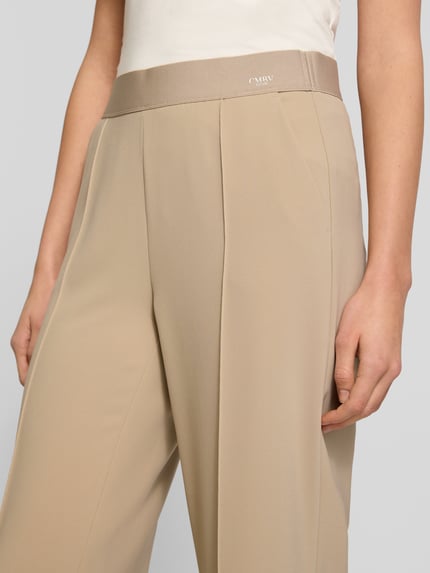 Vrouwenmodel draagt Straight Fit Stoffhose mit Ziernaht Modell 'Cameron' van Cambio, beige, elastische tailleband, logo, detailopname heup en dij.
