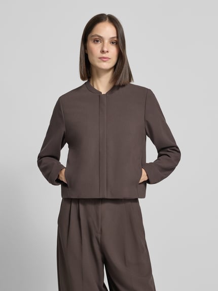 Frauenmodel trägt Blouson mit Viskose-Anteil von COMMA in Braun, lockere Passform, Stehkragen, glatte Textur, Ganzkörperansicht von vorne. Elastischer Material-Mix, Abdeckleiste, elastische Ärmelabschlüsse.
