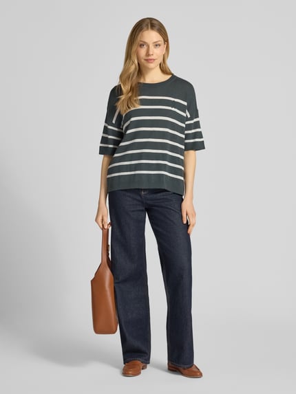 Frauenmodel trägt Relaxed Fit Pullover aus Leinen-Mix Modell 'STRIPE' von Armedangels mit Allover-Muster, Streifen-Design in dunklem Grün mit weißen Streifen, Rundhals, 1/2-Arm, Strick, gerippte Abschlüsse, Logo-Stitching, Materialverarbeitung: Strick, Ganzkörperansicht von vorne.