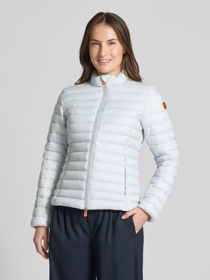 Vrouwenmodel draagt Slim Fit Steppjacke met gewatteerde opstaande kraag Modell 'Carly' van SAVE THE DUCK in lichtblauw, stepp-look, tweewegritssluiting, zakken met rits, ruglengte 58 cm, schouderbreedte 39 cm, borstwijdte 45 cm, mouwlengte 61 cm, vooraanzicht op volledige lichaamslengte.