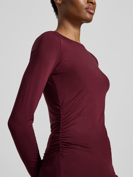Frauenmodel trägt Slim Fit Langarmshirt aus Lyocell-Mix Modell 'AVA' von VERO MODA in dunklem Rot, glatte Textur, Nahaufnahme Oberkörper.