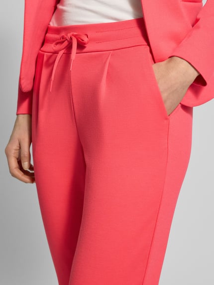 Frauenmodel trägt Slim Fit Stoffhose mit Viskose-Anteil Modell 'Kate' von ICHI in Pink mit elastischem Bund, Eingrifftaschen, Bundfalten, Nahaufnahme Oberkörper. Damen Stoffhose aus Elastischer-Material-Mix mit Viskose-Anteil, Bundweite 38 cm, Innenbeinlänge 65 cm.