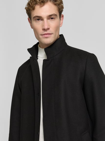 Männermodel trägt Regular Fit Mantel mit Woll-Anteil Modell 'MELTON' von JACK & JONES in Schwarz, Nahaufnahme Oberkörper, glatte Struktur.