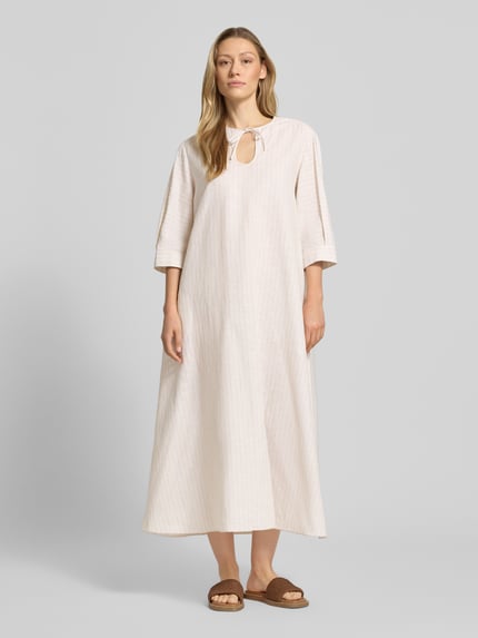 Vrouwenmodel draagt Midikleid aus Leinen-Baumwoll-Mix mit 3/4-Arm van MM by Max Mara, wide fit, model 'MEMO', sleutelgat-halslijn met strik, ruglengte 126 cm, borstwijdte 50 cm, mouwlengte 40 cm, lichte, crèmekleurige stof, vloeiende textuur, geheel vooraanzicht.