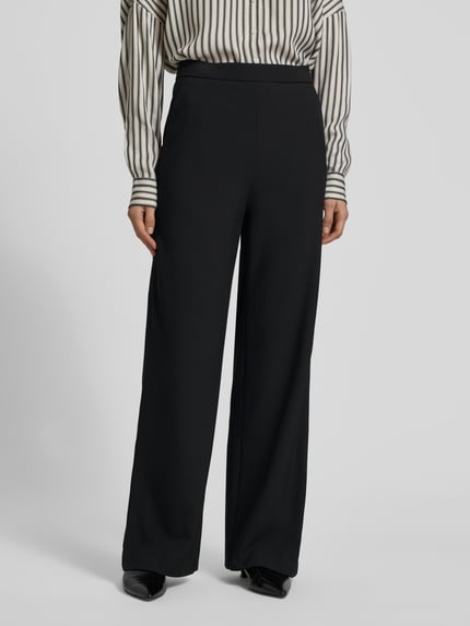 Frauenmodel trägt Wide Leg Stoffhose mit elastischem Bund Modell 'PALINA' von Raffaello Rossi, Material-Mix mit Viskose-Anteil, Crêpe-Struktur, französische Eingrifftaschen, Gesäßtaschen, schwarze Farbe, Ganzkörperansicht von vorne.