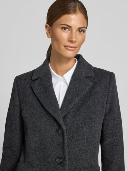 Vrouwenmodel draagt 'Mantel uit wolmix met reverskraag en klepzakken' van FUCHS SCHMITT in donkergrijs met knoopsluiting, straight fit, met wol en kasjmier, reverskraag en klepzakken, ruglengte maat 36: 95 cm, schouderbreedte: 42 cm, borstwijdte: 48 cm, mouwlengte: 66 cm, close-up bovenlichaam.