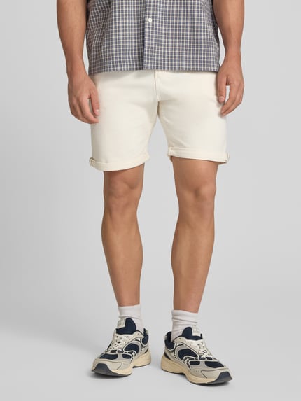 Männermodel trägt Jeansshorts mit Umschlag und Eingrifftaschen Modell 'RICK ALLEN' von Jack & Jones im Baumwoll-Elasthan-Mix, Regular-Fit, Farbe creme, glatte Struktur, Bundweite 43 cm, Innenbeinlänge 20 cm, Nahaufnahme Oberkörper bis Knie.